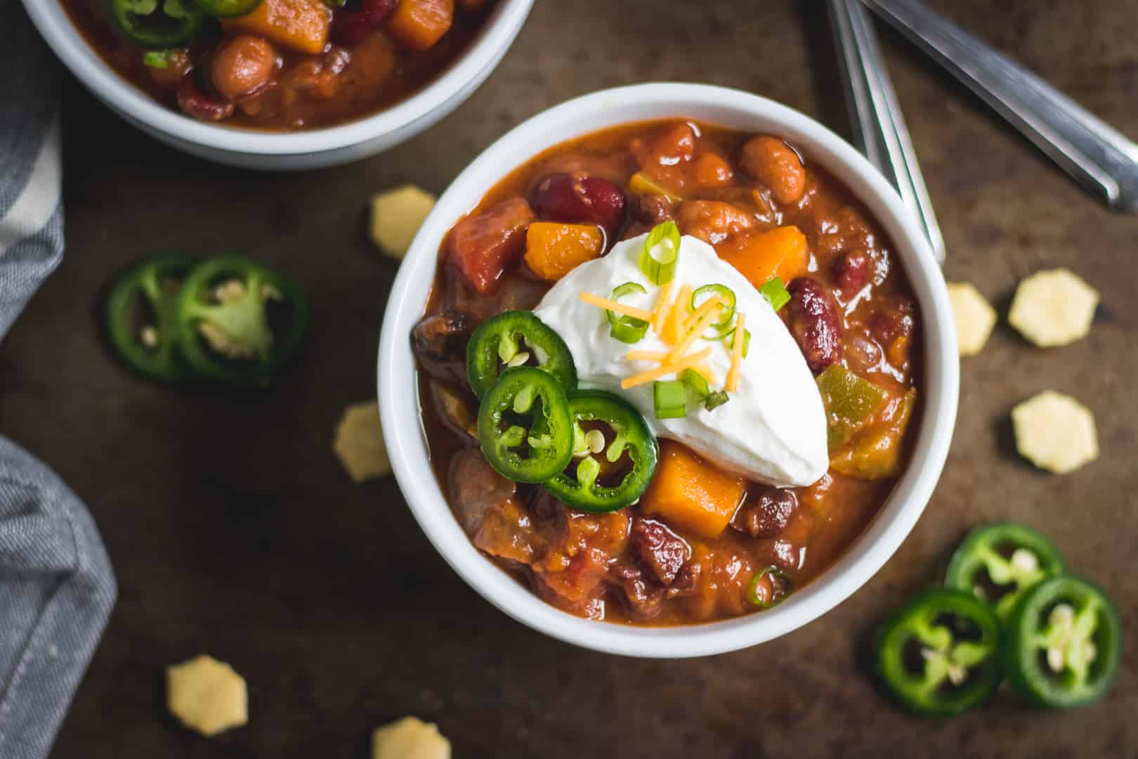Overhead photo of slow cooker sweet potato chili with toppings, crackers and jalapeños.