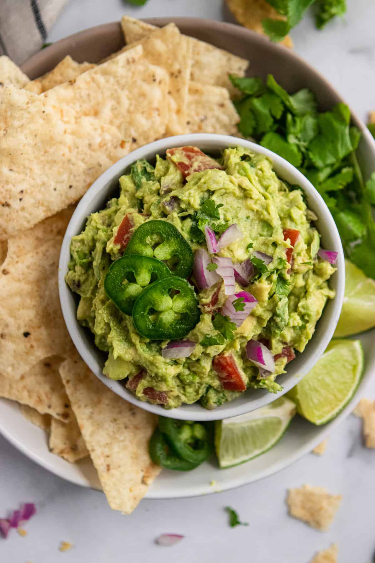 Bowl of simple guacamole with chips, lime and cilantro.