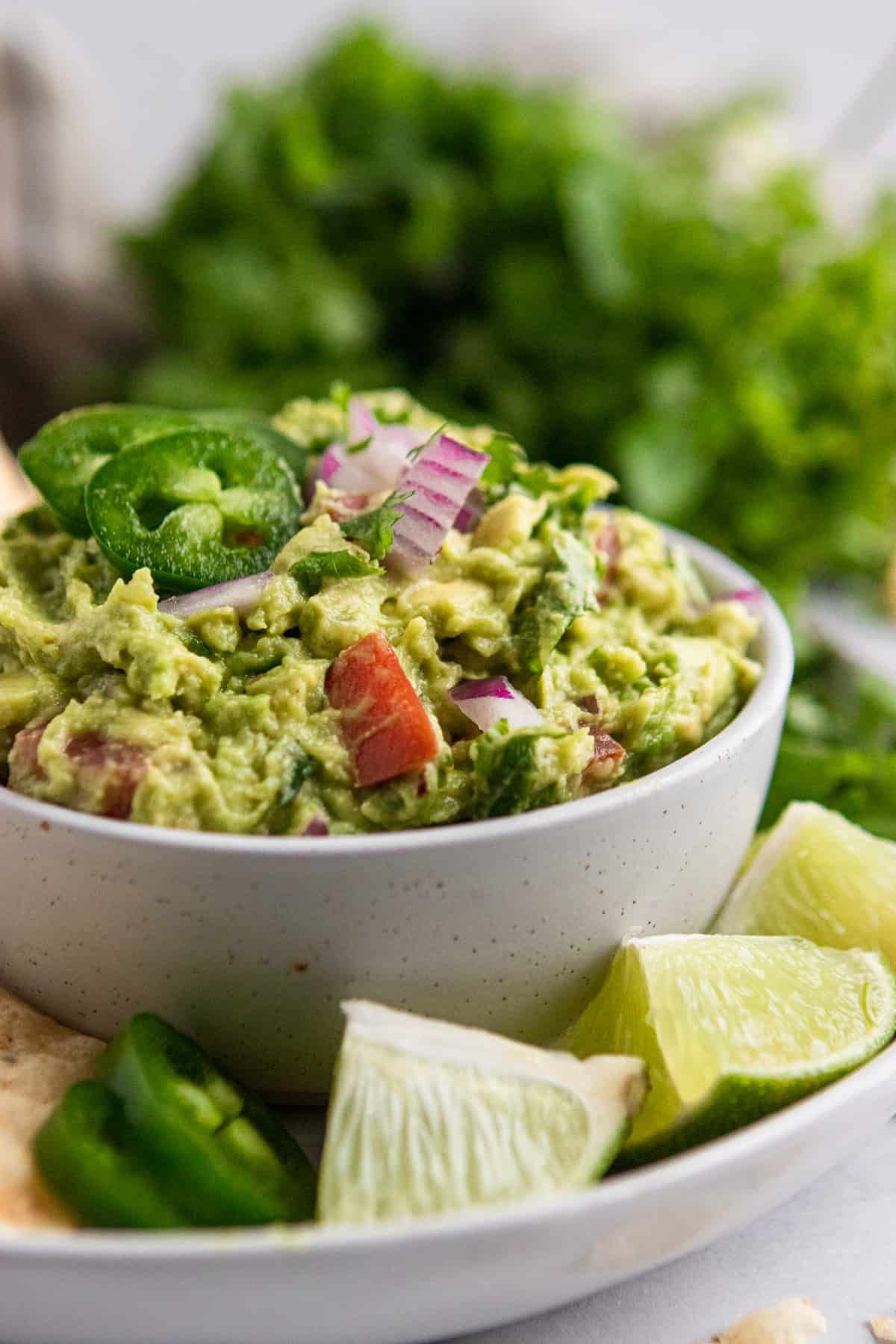 Healthy guacamole recipe on plate with limes.