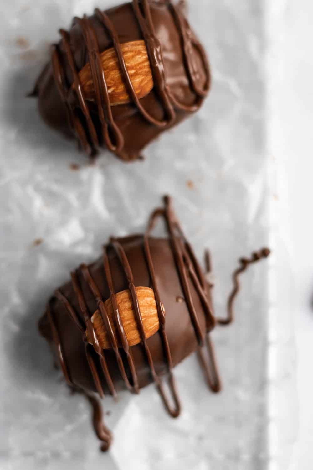 Overhead view of chocolate coated coconut candy with almond and chocolate drizzle.