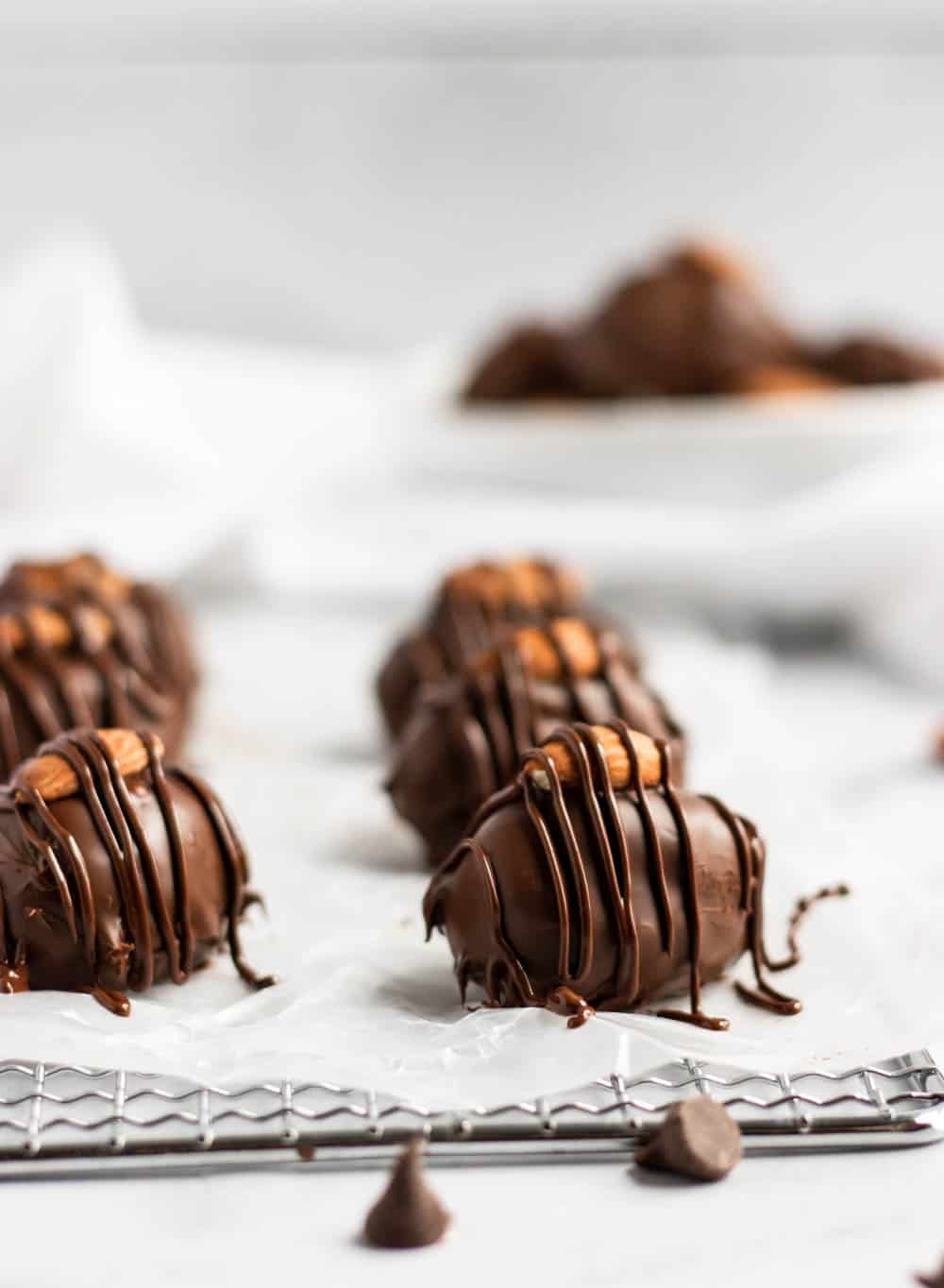 Homemade almond joy bars with chocolate drizzle on wax paper.