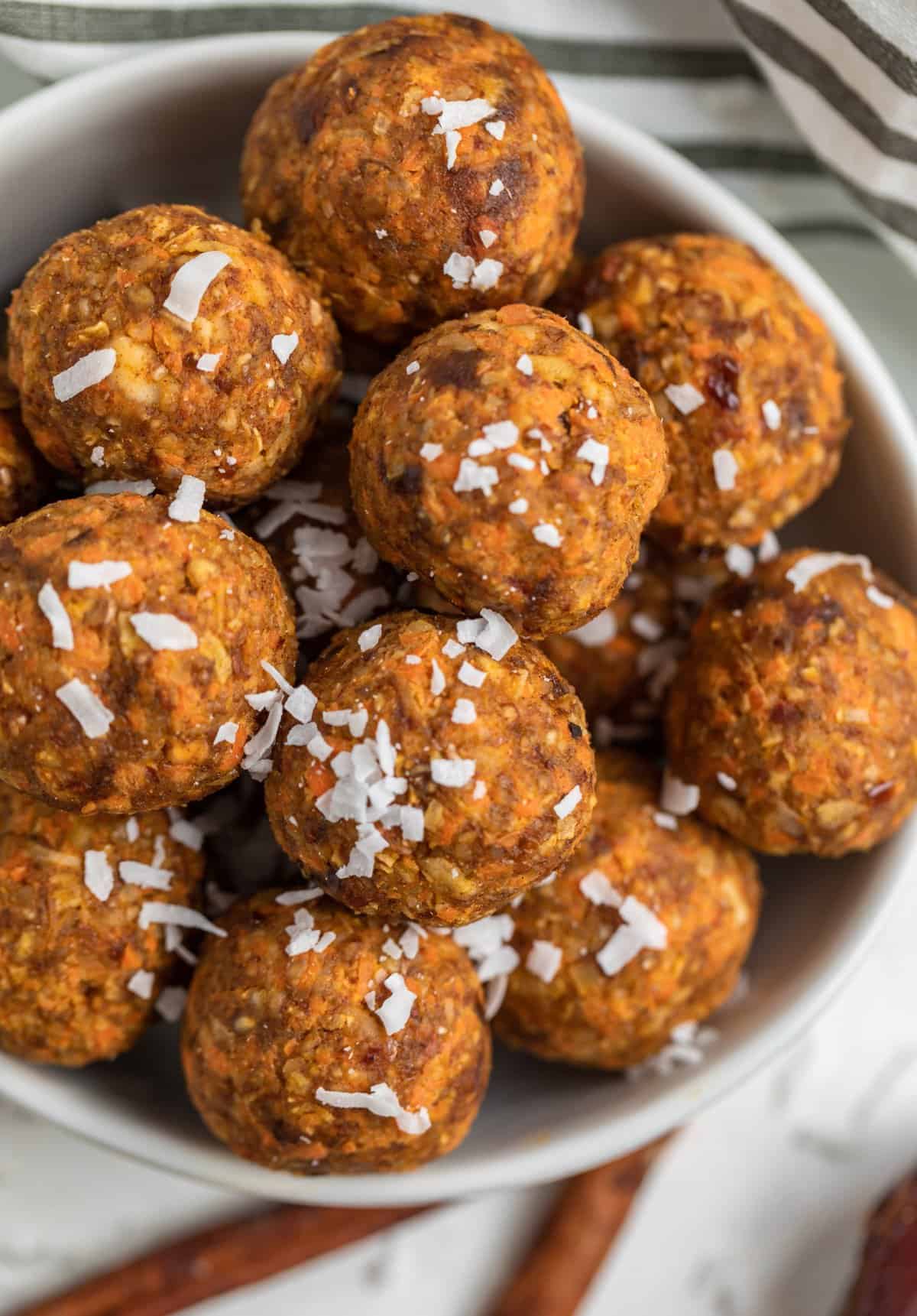 Bowl of carrot cake balls with shredded coconut on top.
