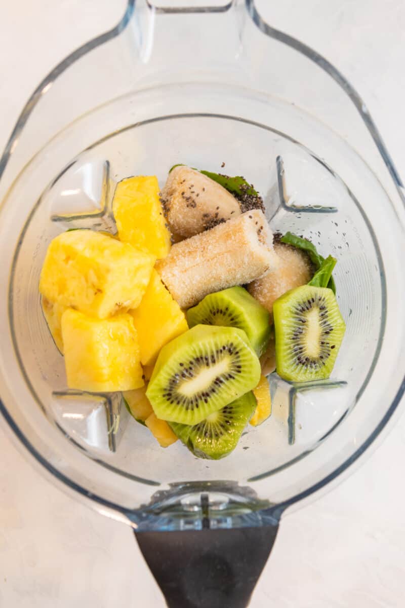 Pineapple, banana, kiwi and other ingredients in blender.