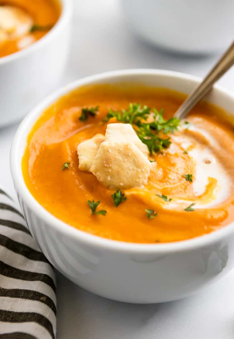 Maple Roasted Sweet Potato Carrot Soup in bowl with parsley and cream.