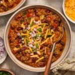 Bowl of chili with quinoa, pumpkin, beans and spoon scooping in.