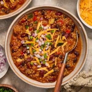 Bowl of chili with quinoa, pumpkin, beans and spoon scooping in.