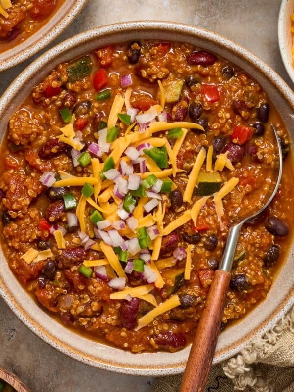 Bowl of chili with quinoa, pumpkin, beans and spoon scooping in.
