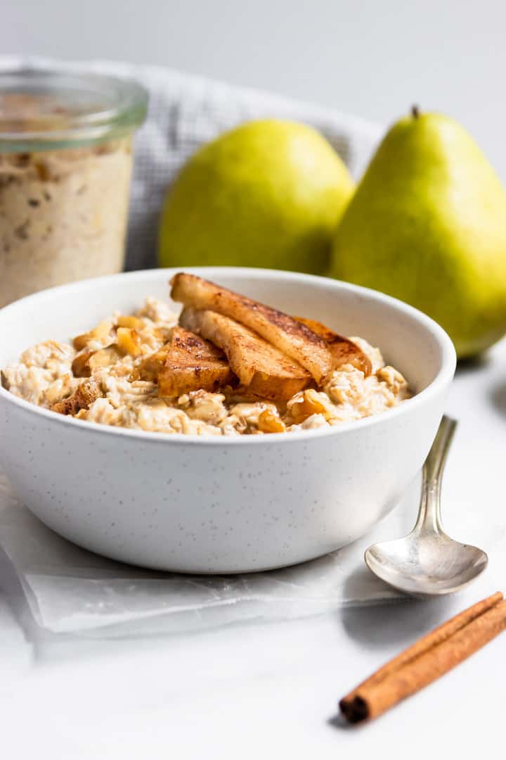 Cinnamon pears on top of oatmeal in white bowl.