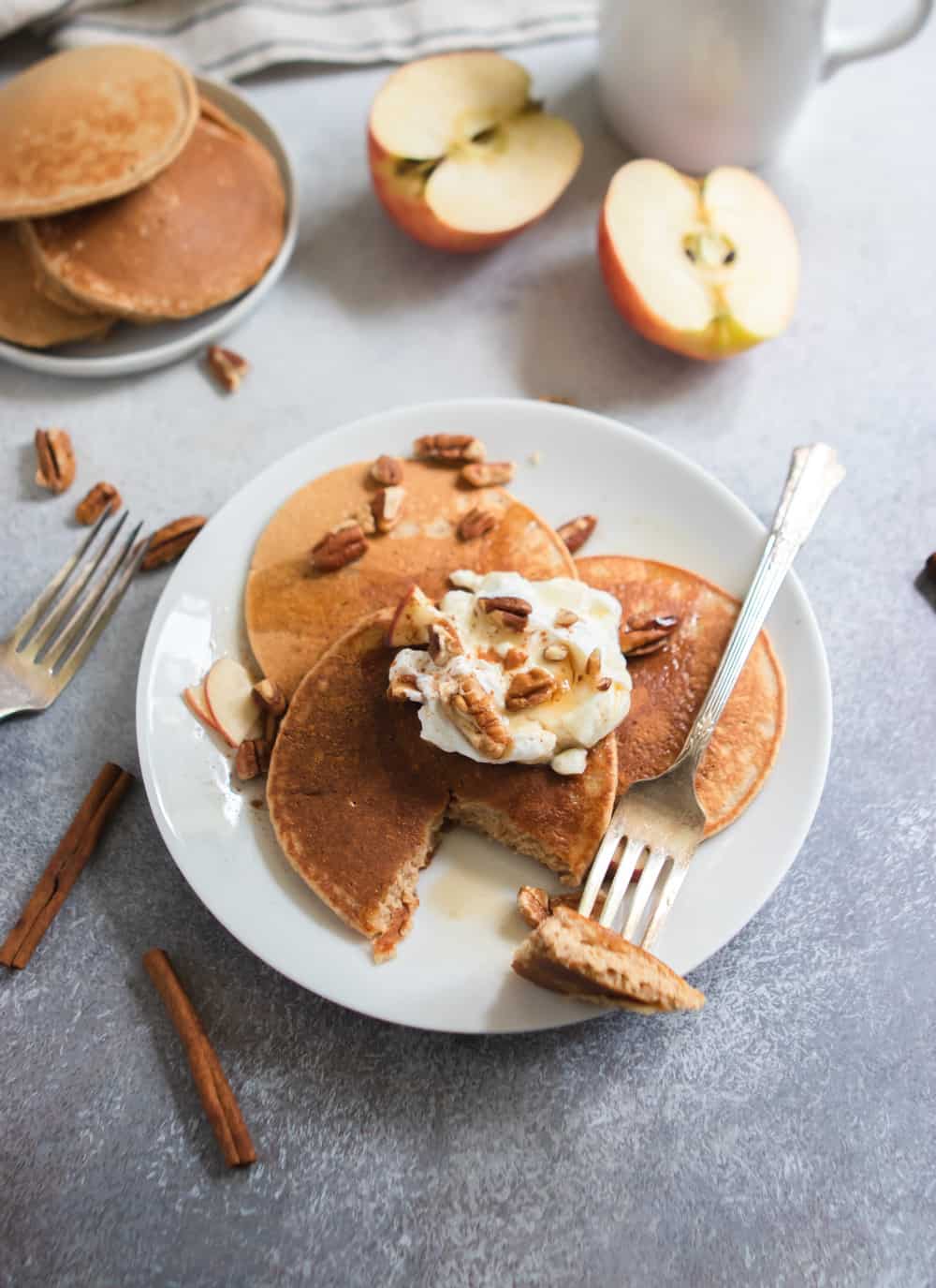 Apple oatmeal pancakes with maple syrup, pecans and yogurt.