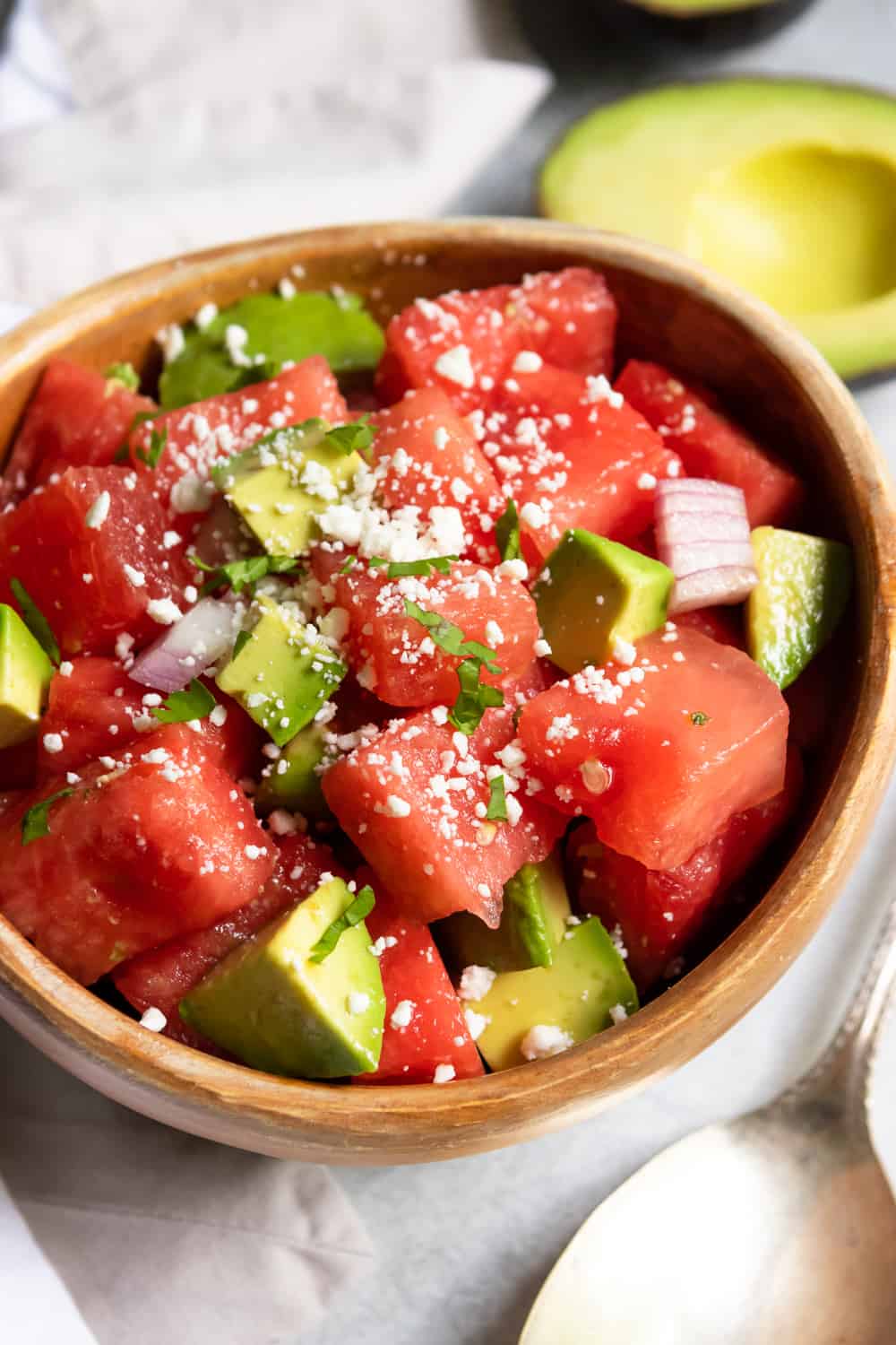 Watermelon feta salad in wood bowl with fresh cilantro and red onion.