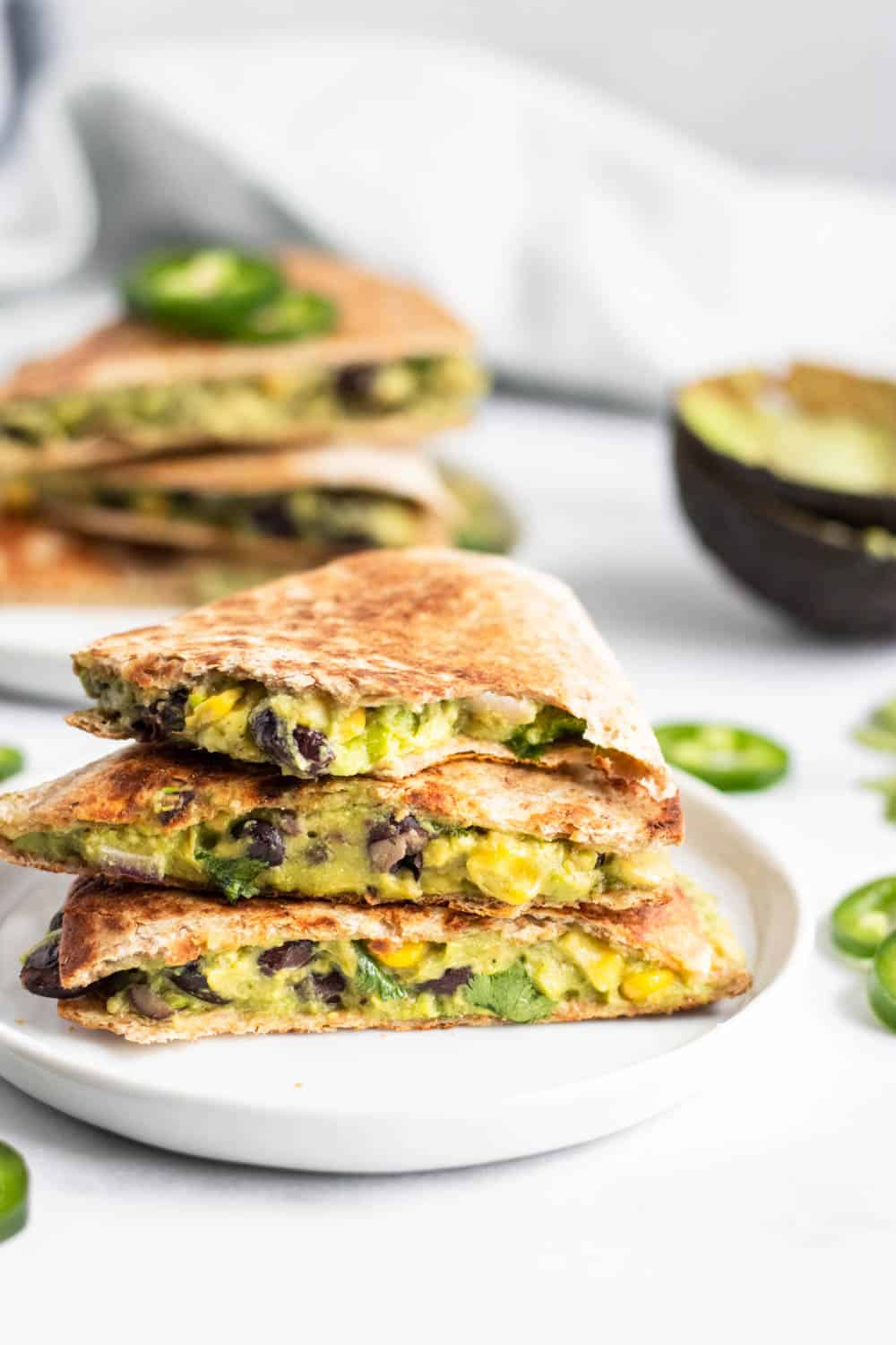 Bite shot of Vegan Black Bean quesadillas with avocado on white plate.