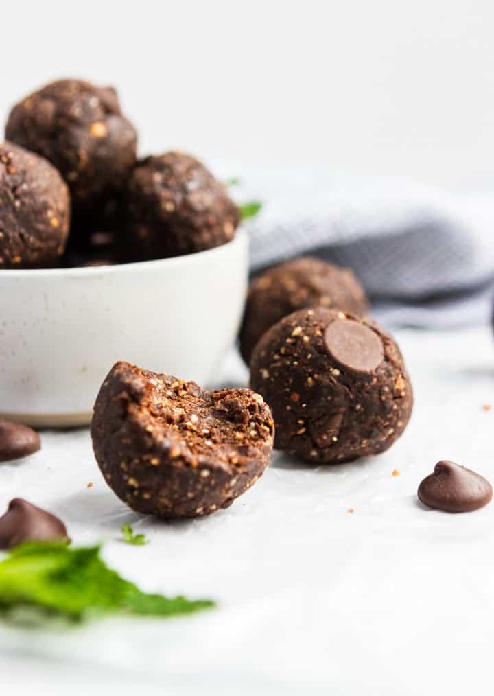 Bite shot of no bake brownie bite with mint leaf and chocolate chip.