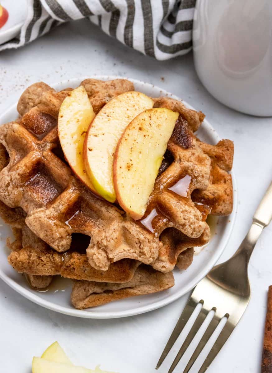 Vegan waffles with syrup and sliced apple.