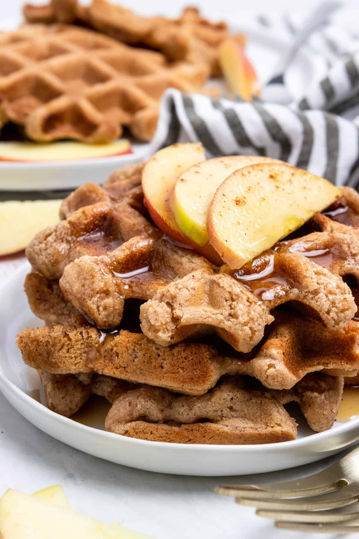 Stack of waffles with apples on top.