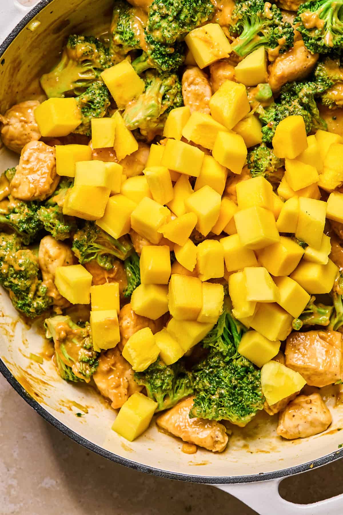 Cubed mango added to pan with chicken and vegetables.