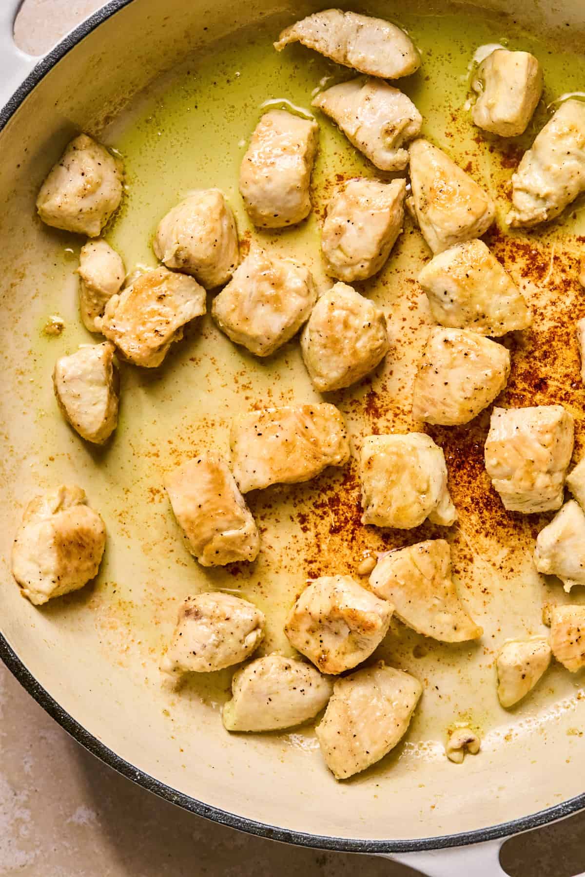Seasoned chicken browned in skillet.