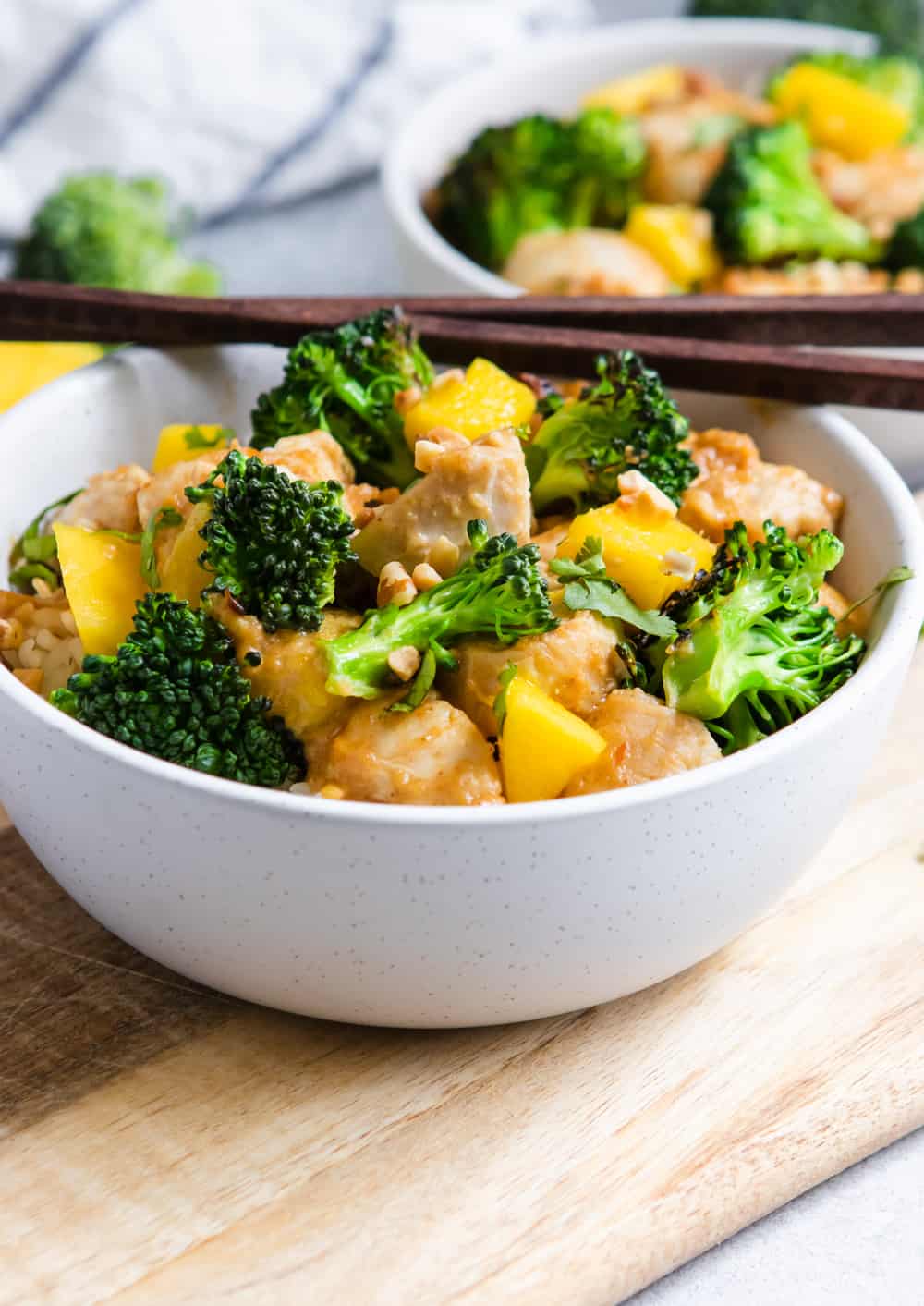 Peanut Mango Chicken and Broccoli Stir Fry in bowl with chopsticks.