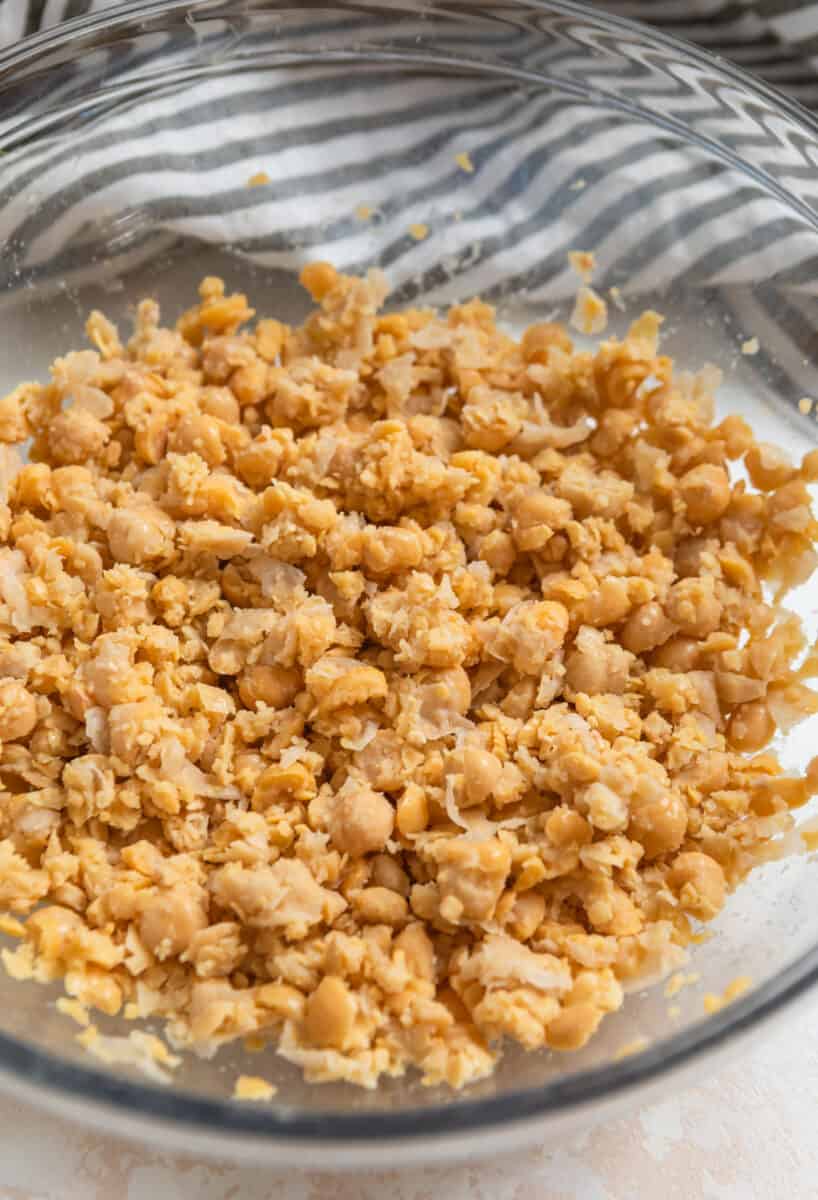 Chickpeas mashed in glass mixing bowl,