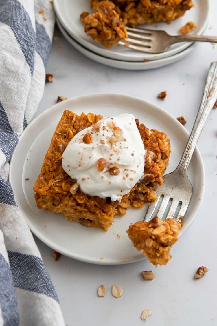 Piece of pumpkin baked oatmeal on plate with yogurt and pecans.