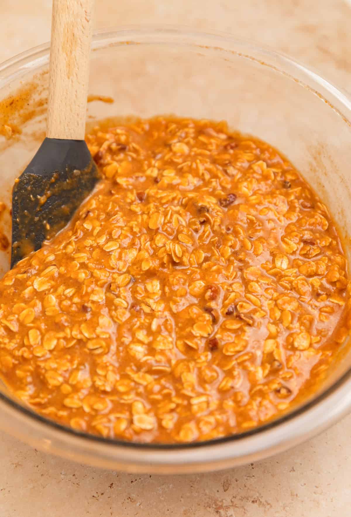 Spatula propped in bowl with pumpkin oatmeal mixture.