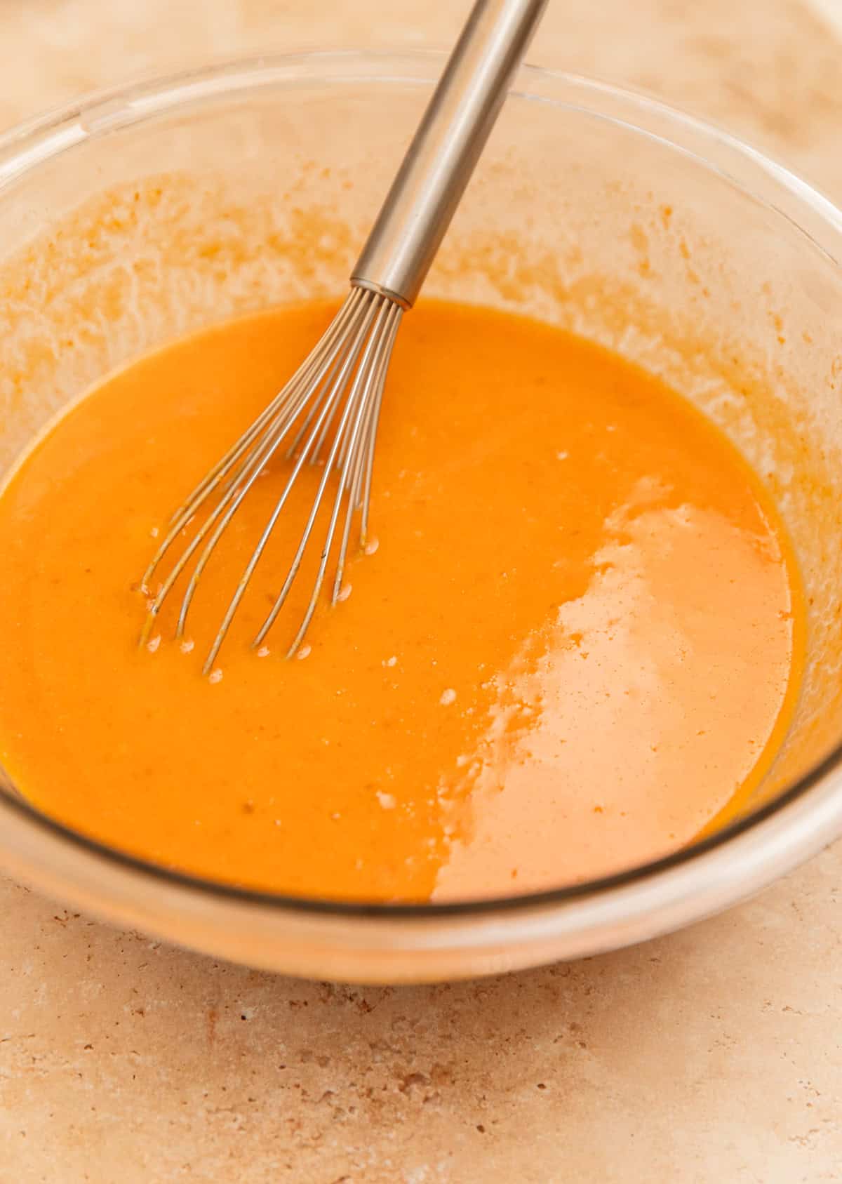 Pumpkin and egg mixture in bowl with whisk.