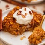 Slice of pumpkin oatmeal bake topped with yogurt and chopped pecans.