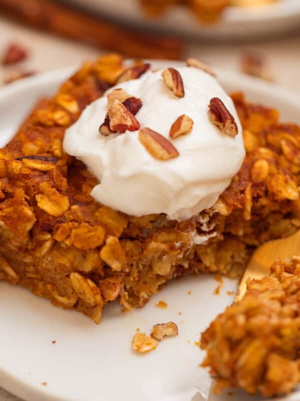 Slice of pumpkin oatmeal bake topped with yogurt and chopped pecans.