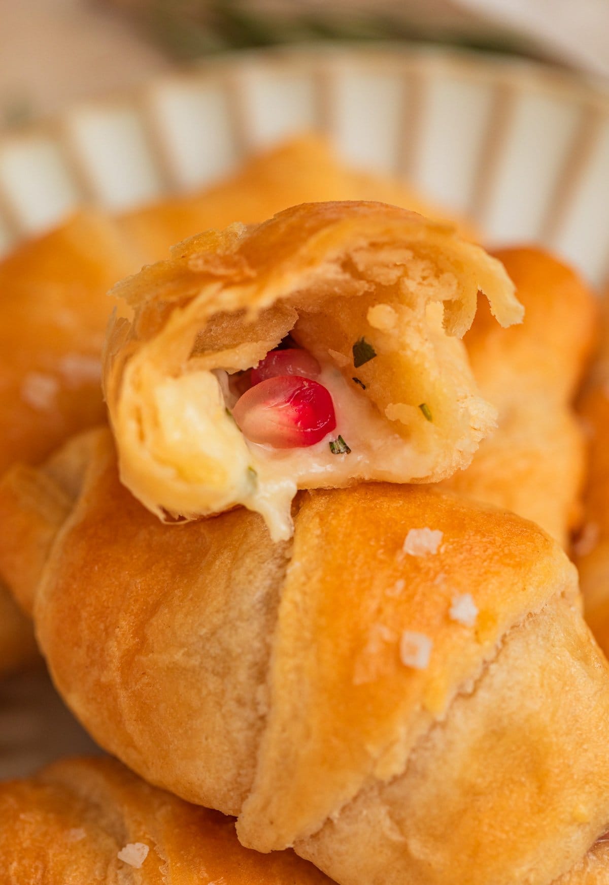 Halved crescent roll with cheese and pomegranate inside.