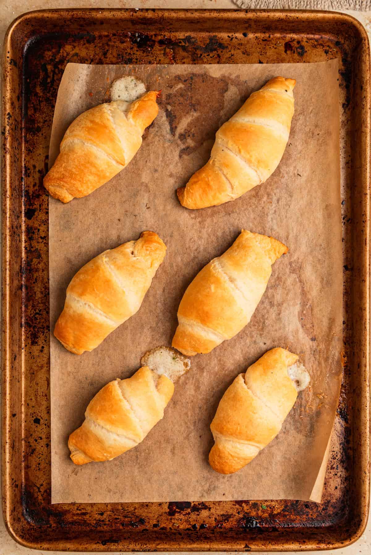 Baked stuffed crescent rolls parchment lined baking sheet.