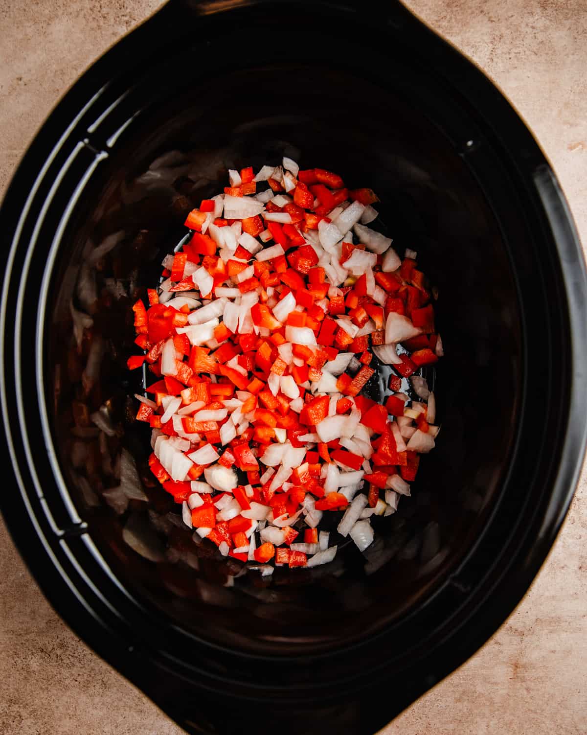 Red pepper and onion chopped at the bottom of crockpot.