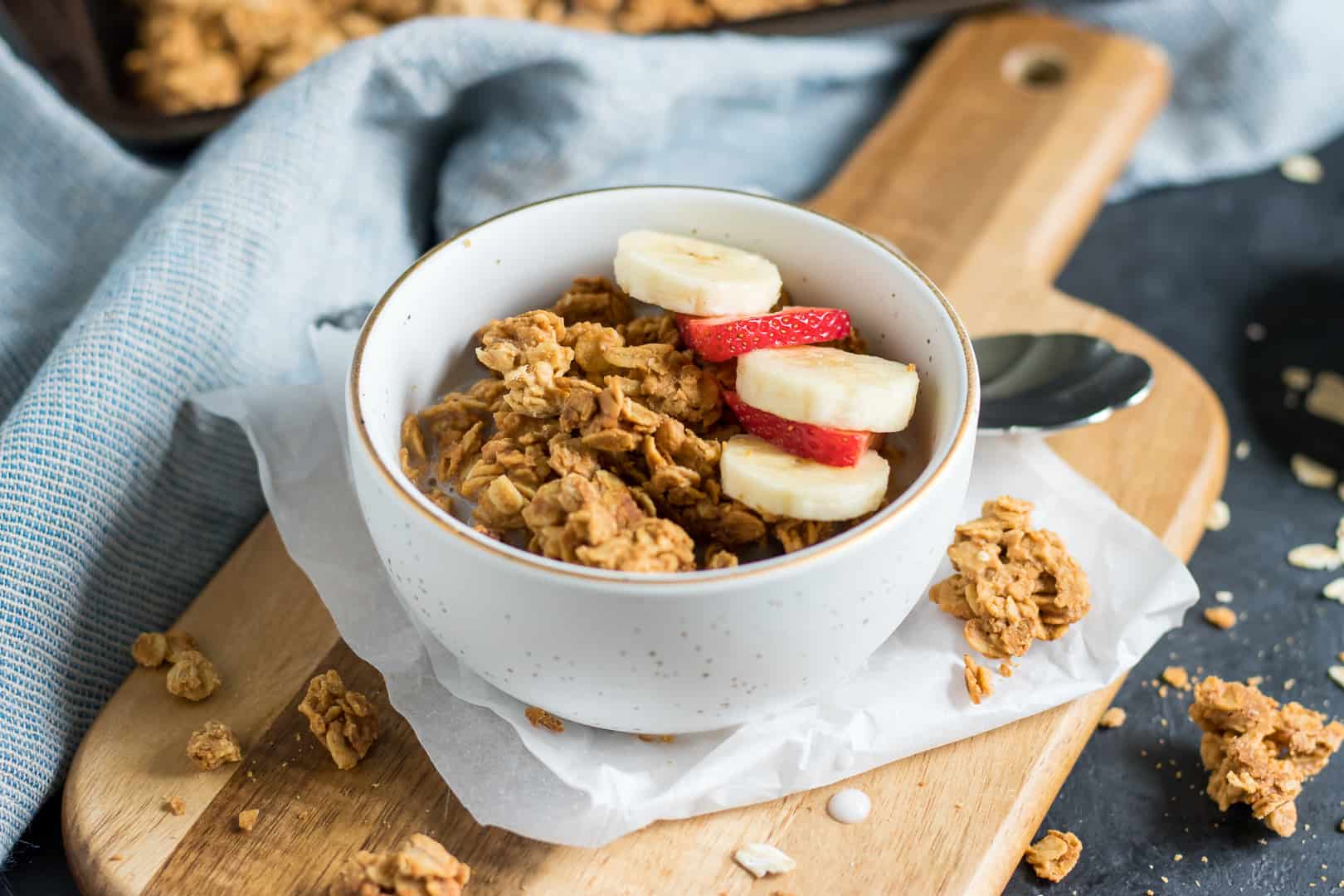 Peanut butter granola in bowl with banana and strawberry slices.