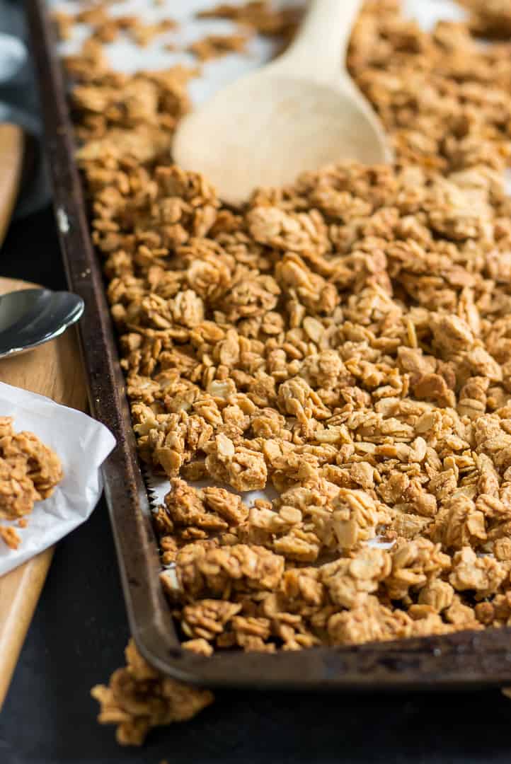 Crunchy Peanut Butter Granola on baking pan with wooden spoon.