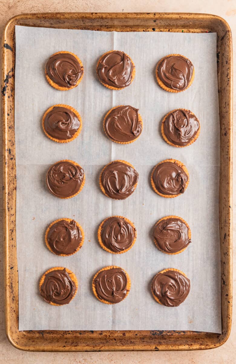 Nutella spread on Ritz crackers arranged on cookie sheet.