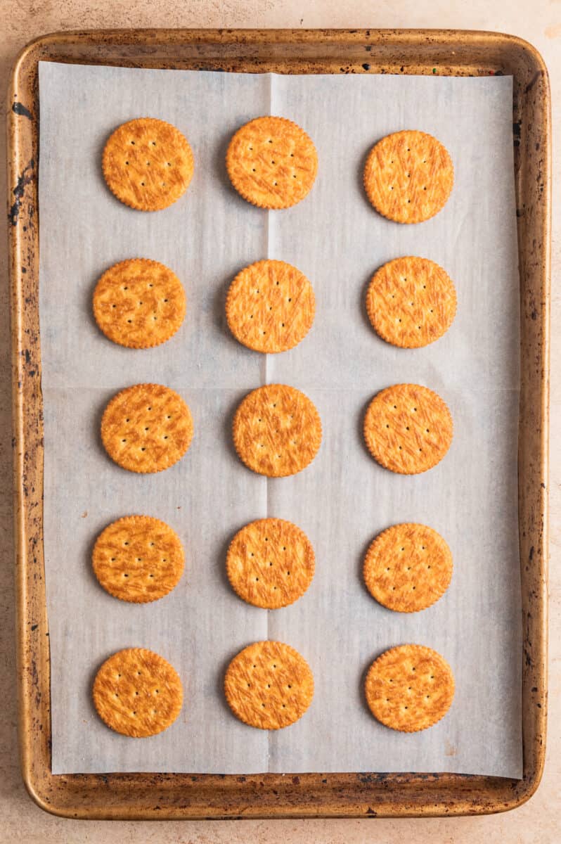 Ritz crackers arranged on parchment paper lined cooke sheet.