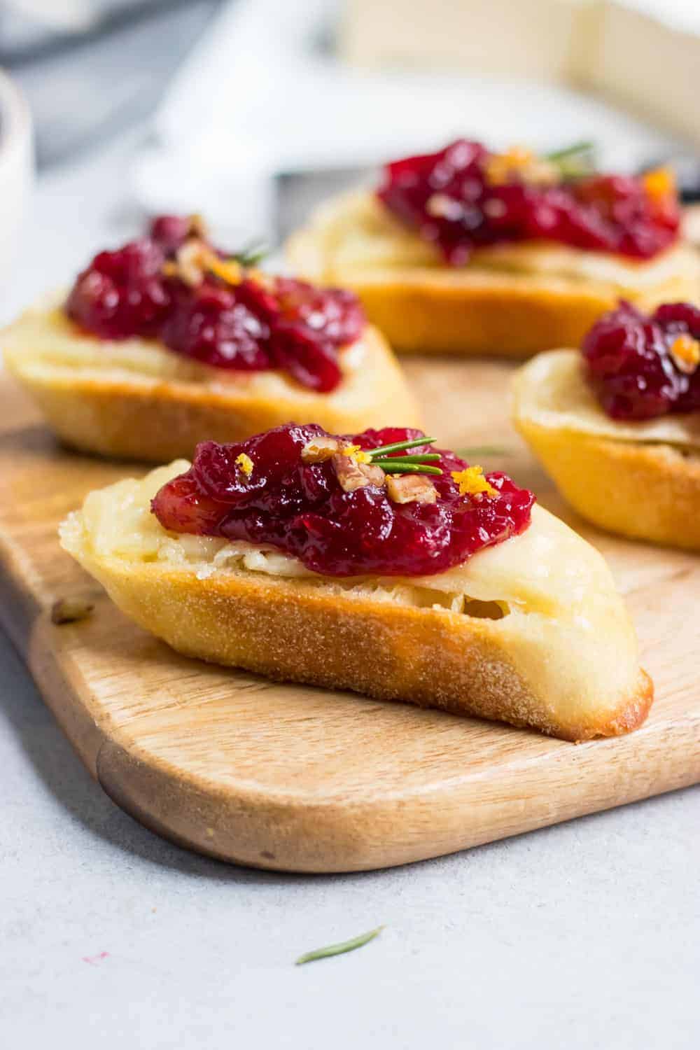Cranberry brie crostini with fresh rosemary and chopped pecans on top.