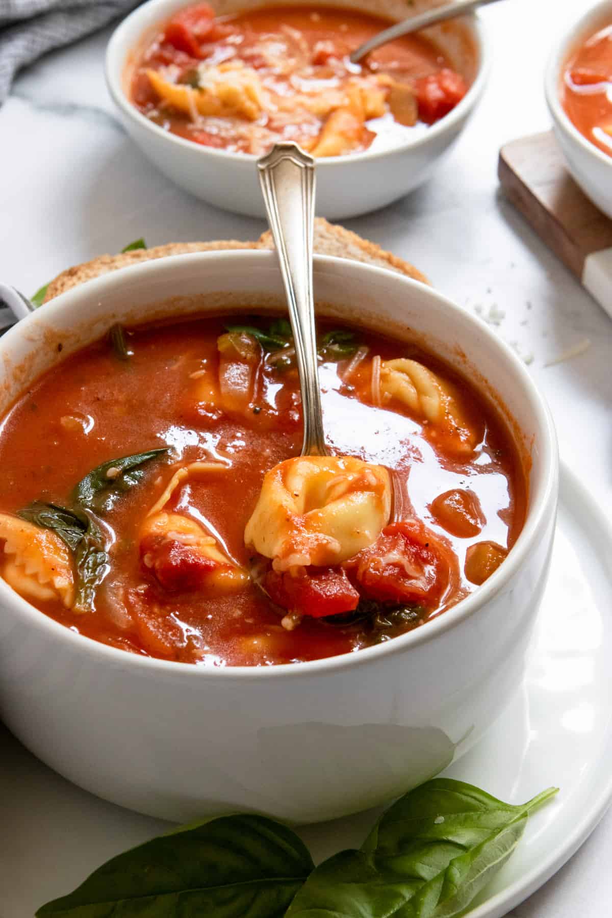 Spoon in soup bowl with tortellini in it.