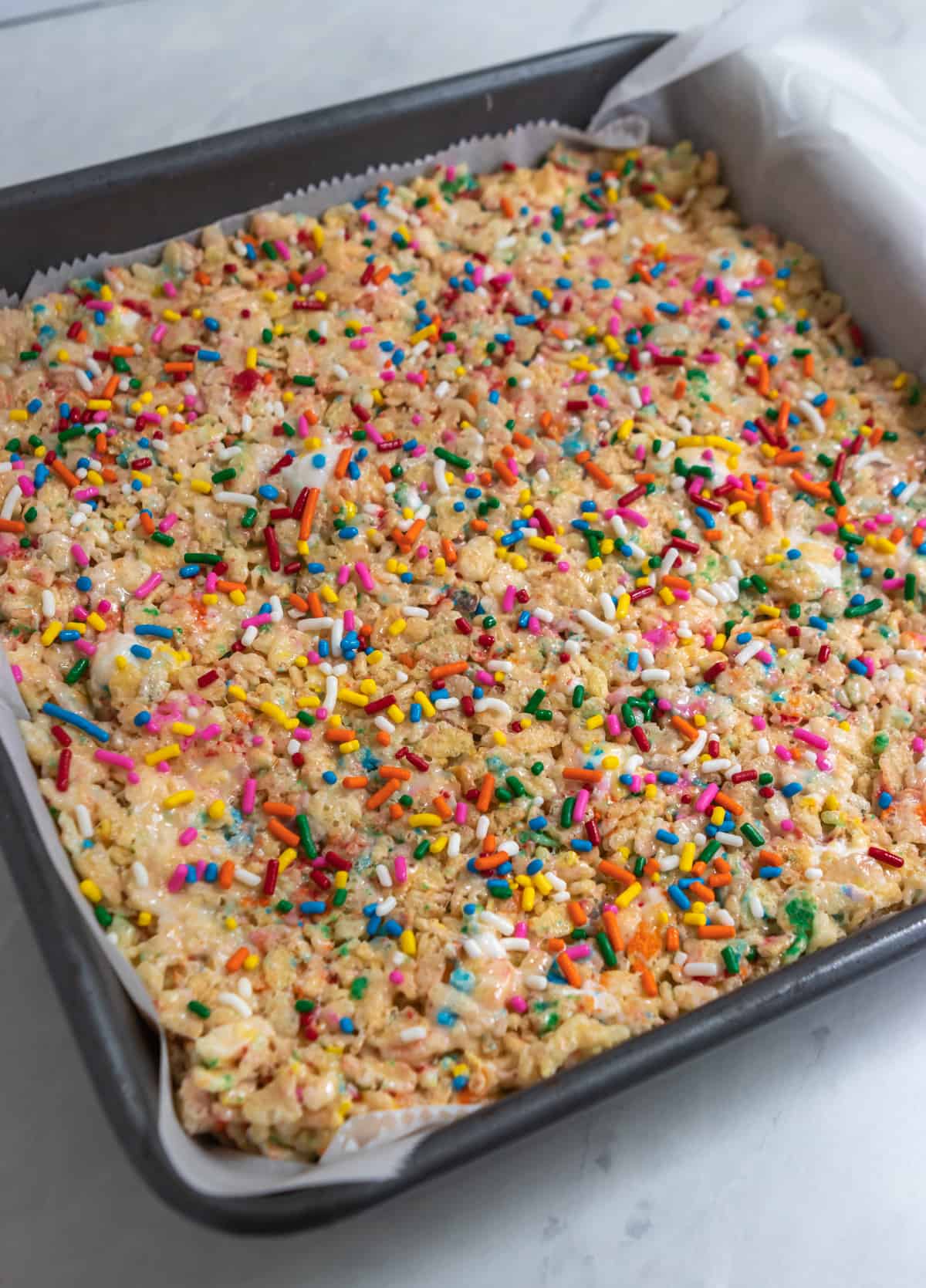 Pan with Rice Krispie Treats and rainbow sprinkles on top.