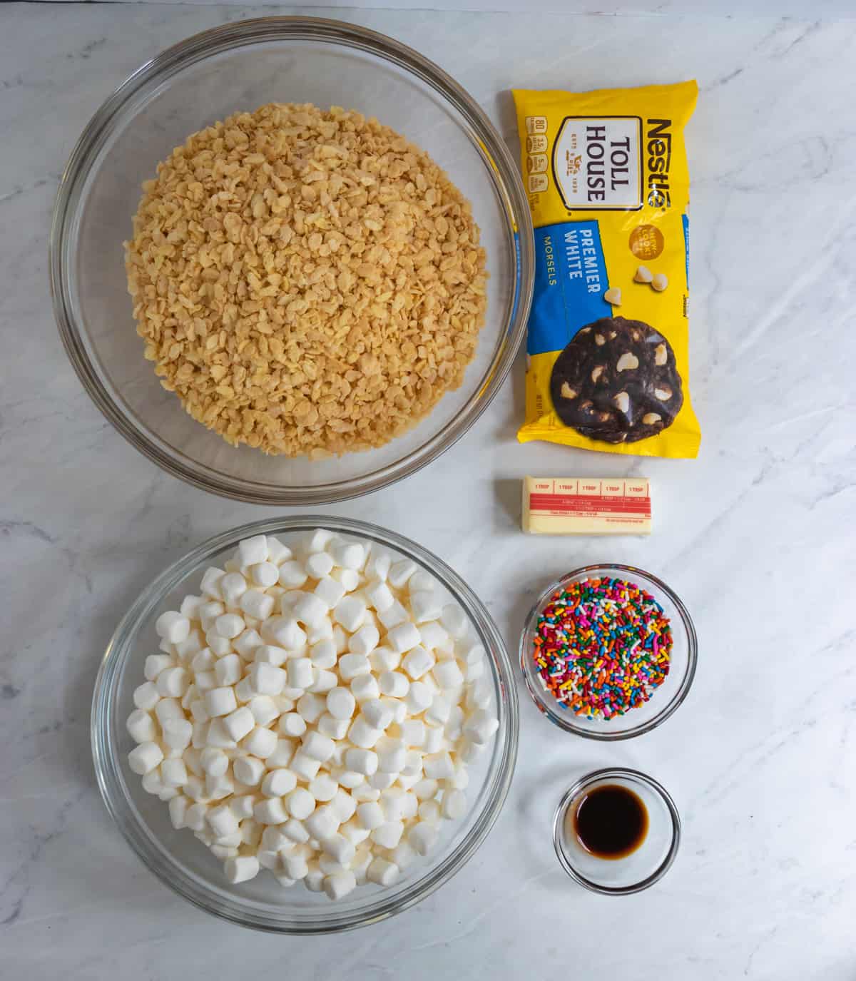 Cereal, marshmallows, sprinkles, white chocolate and ingredients on counter.