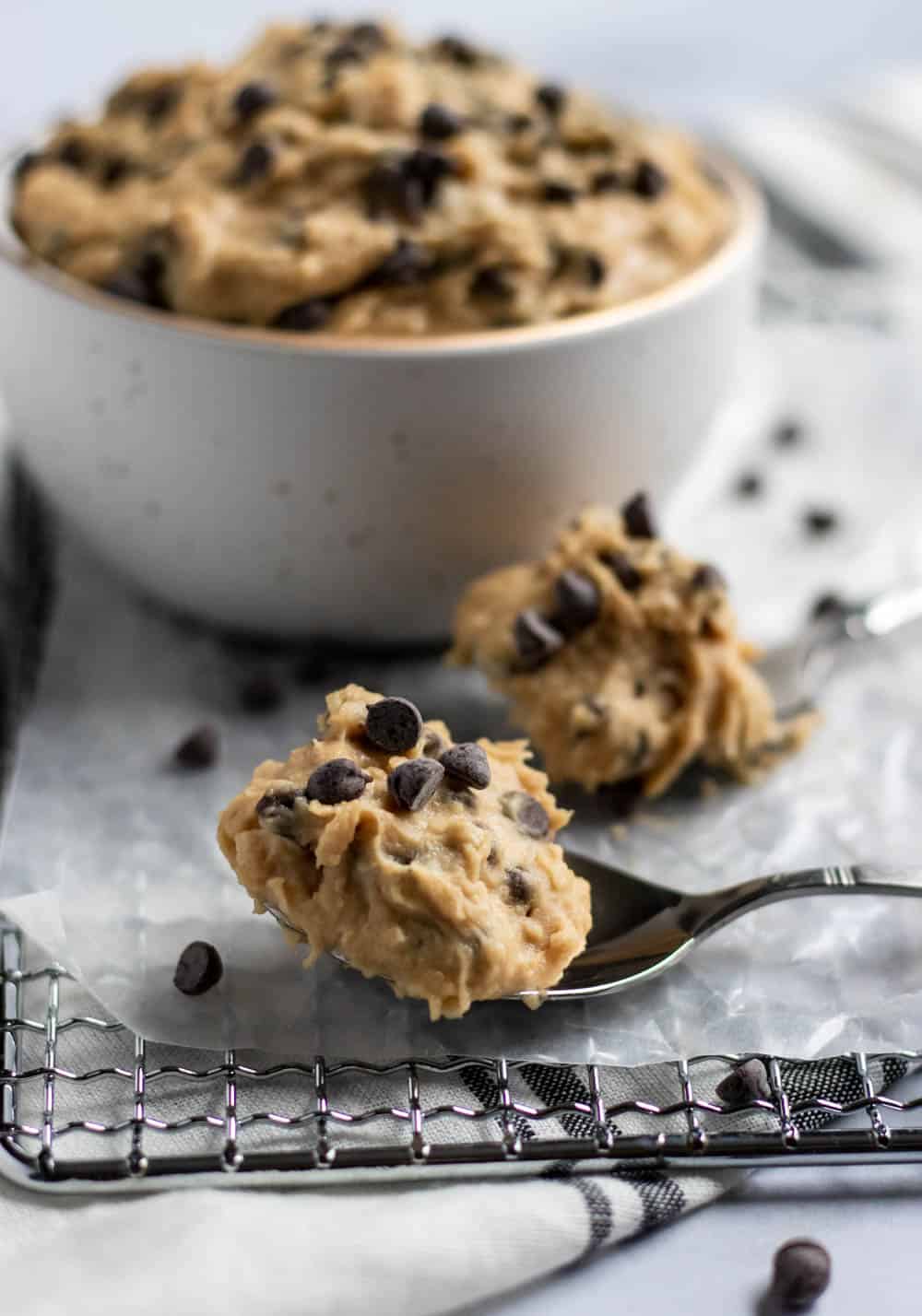 cookie dough on spoons in front of bowl.