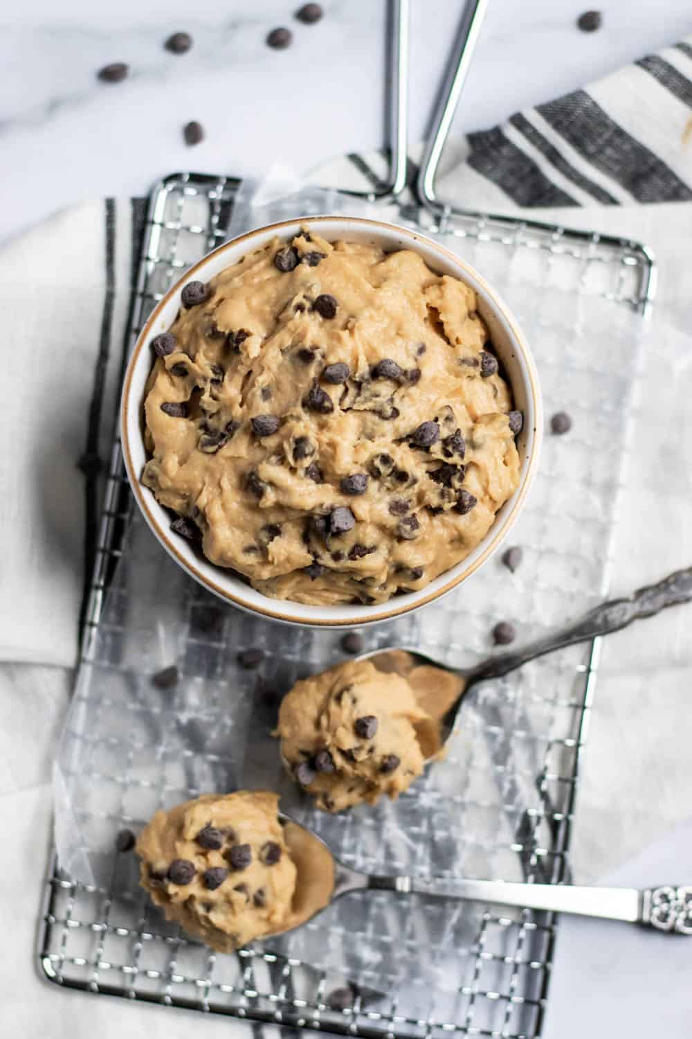 Bowl of cookie dough on wax paper with spoons.