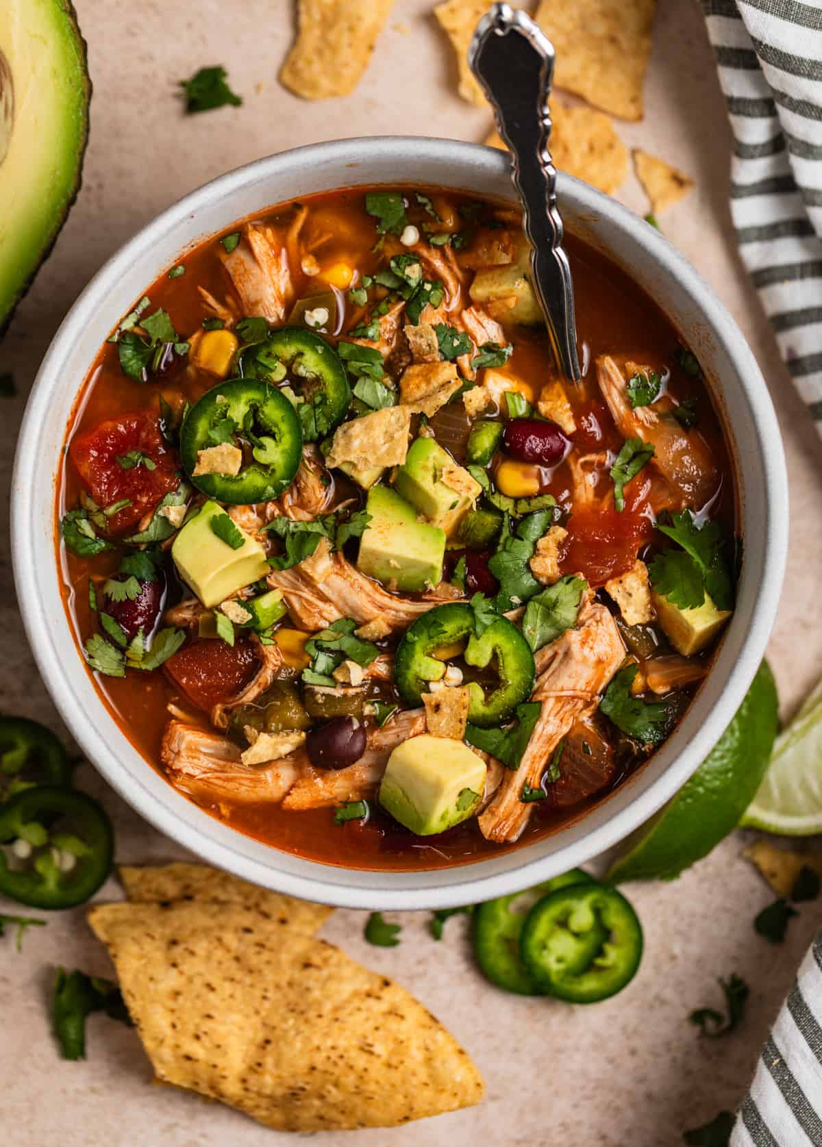 Soup bowl with Instant Pot Chicken Tortilla soup topped with cilantro, tortilla chips, jalapeño, etc.