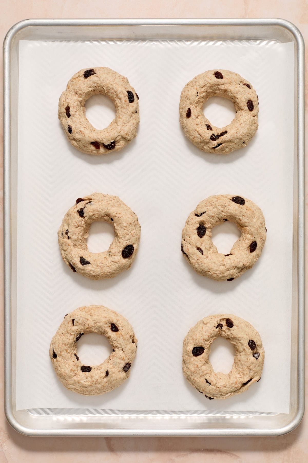 Bagels formed and arranged on baking sheet before baking.