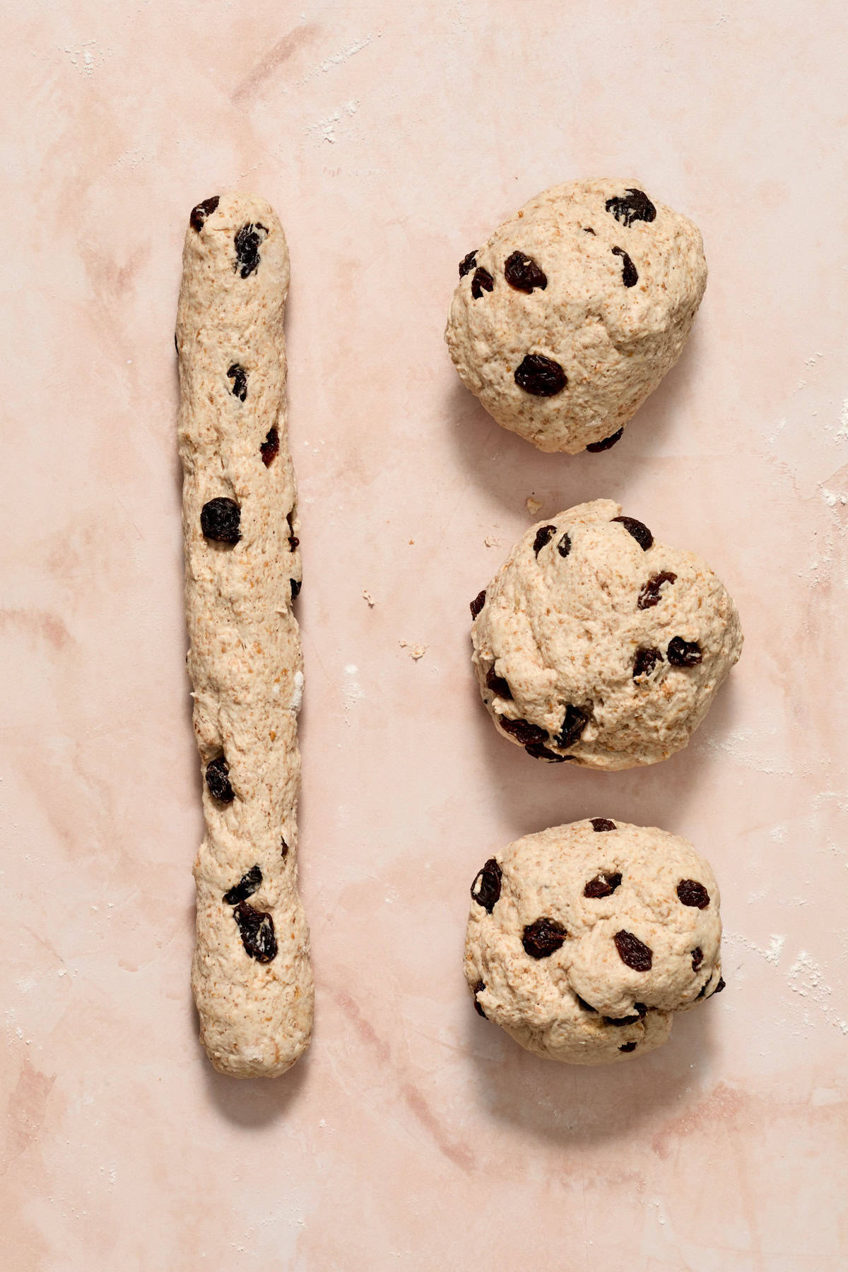 Raisin and cinnamon dough in balls and then one rolled into a long thin strip.