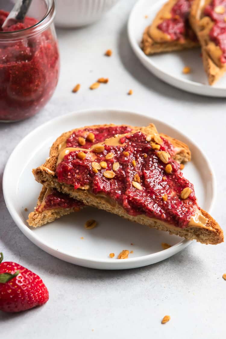 Strawberry chia jam on peanut butter toast slices on white plate.