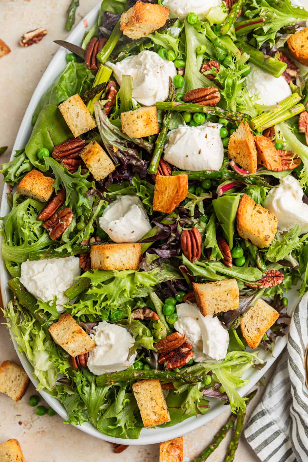 Overhead view of serving platter with spring green and burrata salad.