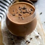 Chocolate smoothie in glass with cacao nibs on top.