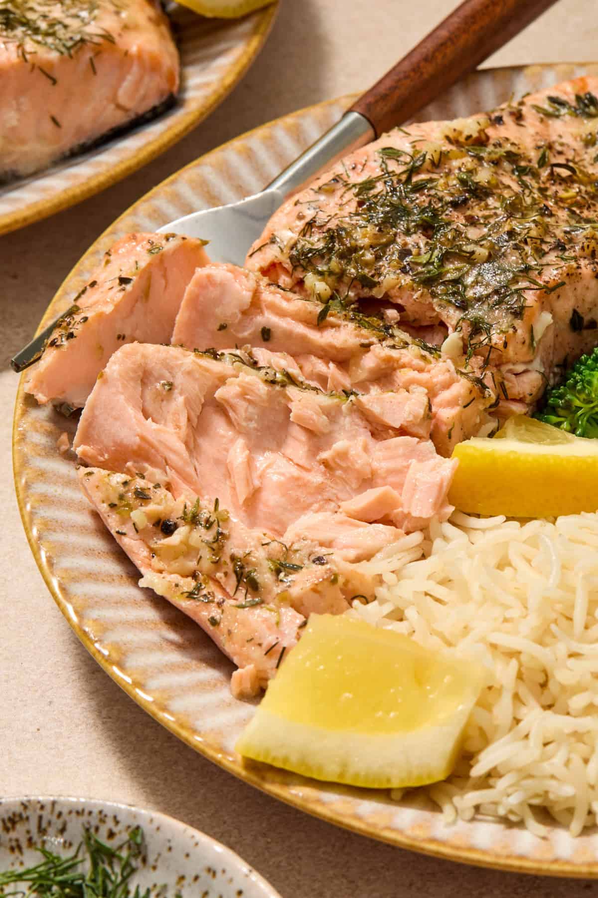 Salmon flaked to show texture on plate with rice and lemon wedges.