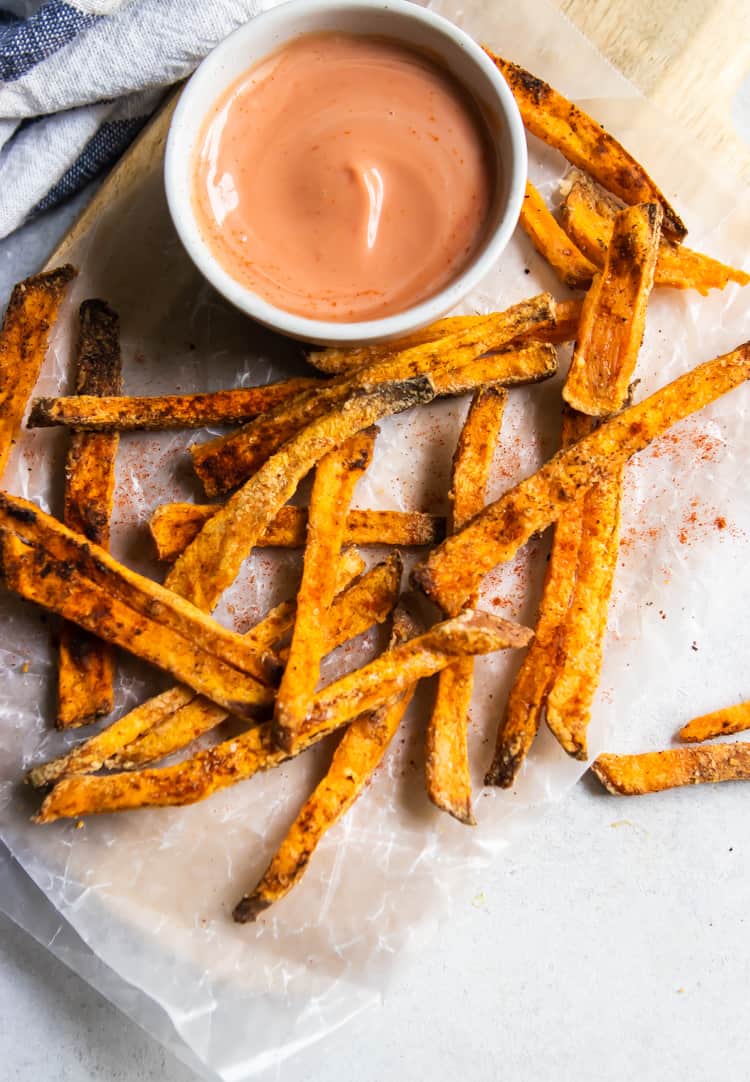 Sweet potato fries on wax paper with dip.