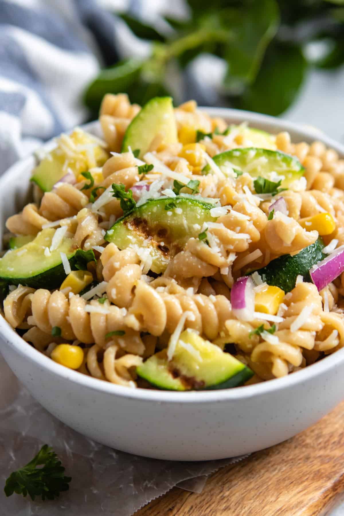 Zucchini pasta salad in bowl with fresh corn and shredded parmesan.