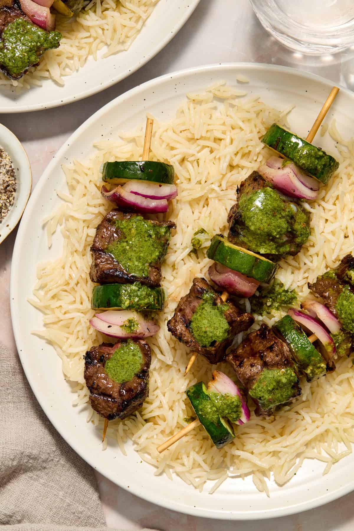 Grilled steak kabobs with zucchini and onion over rice and topped with cilantro chimichurri.